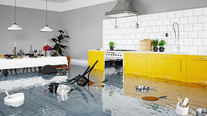 Kitchen with yellow cabinets and standing water on the floor after a leak